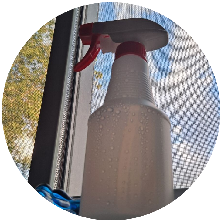 A spray bottle with clear liquid, on a windowsill with blue sky behind it to fix your vegetable dirt skin stains